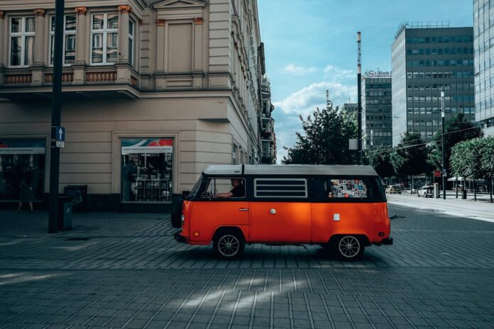 Person Driving an Orange Volkswagen Type 2 on Street